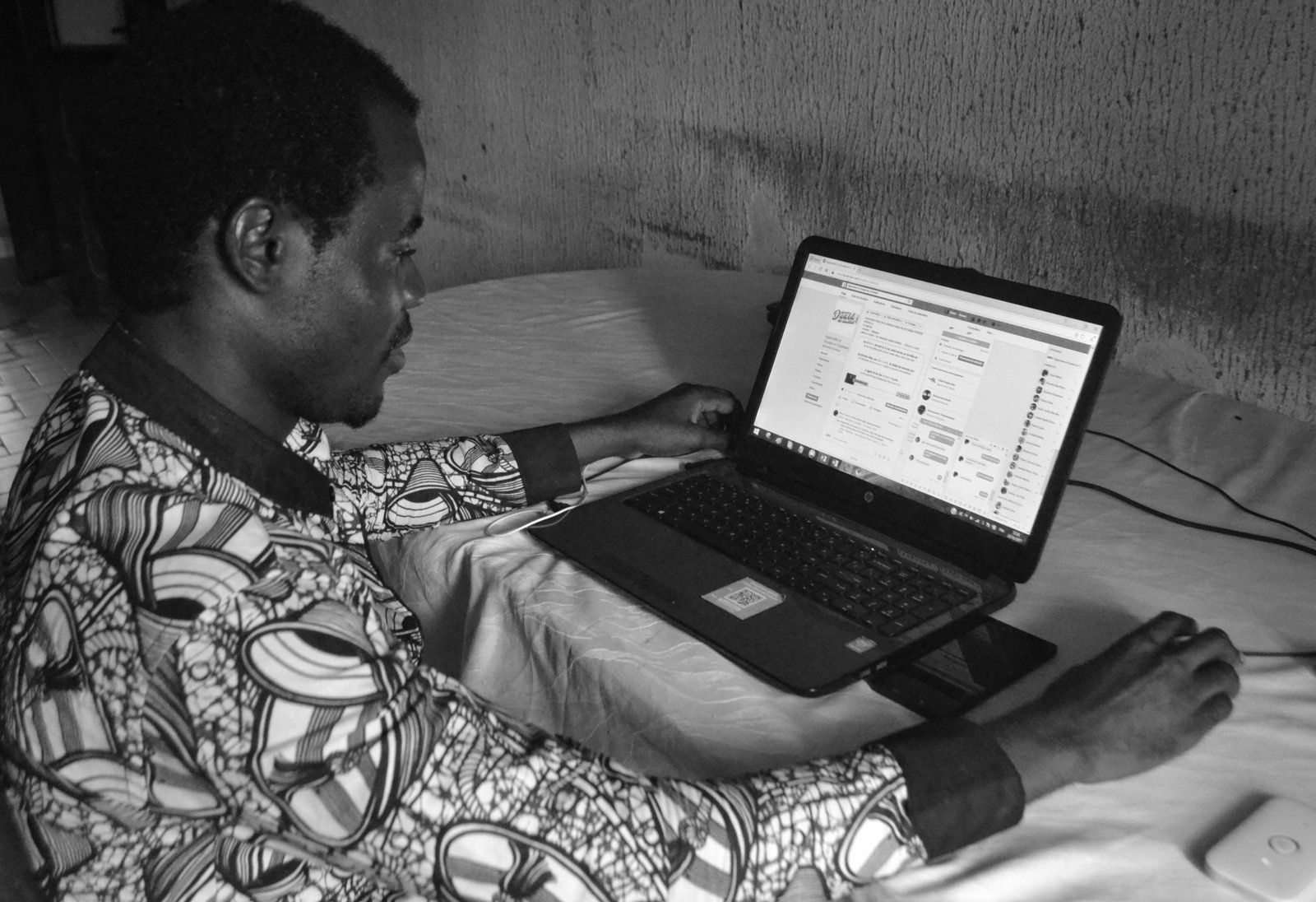 A person in Cameroon working on a laptop computer.